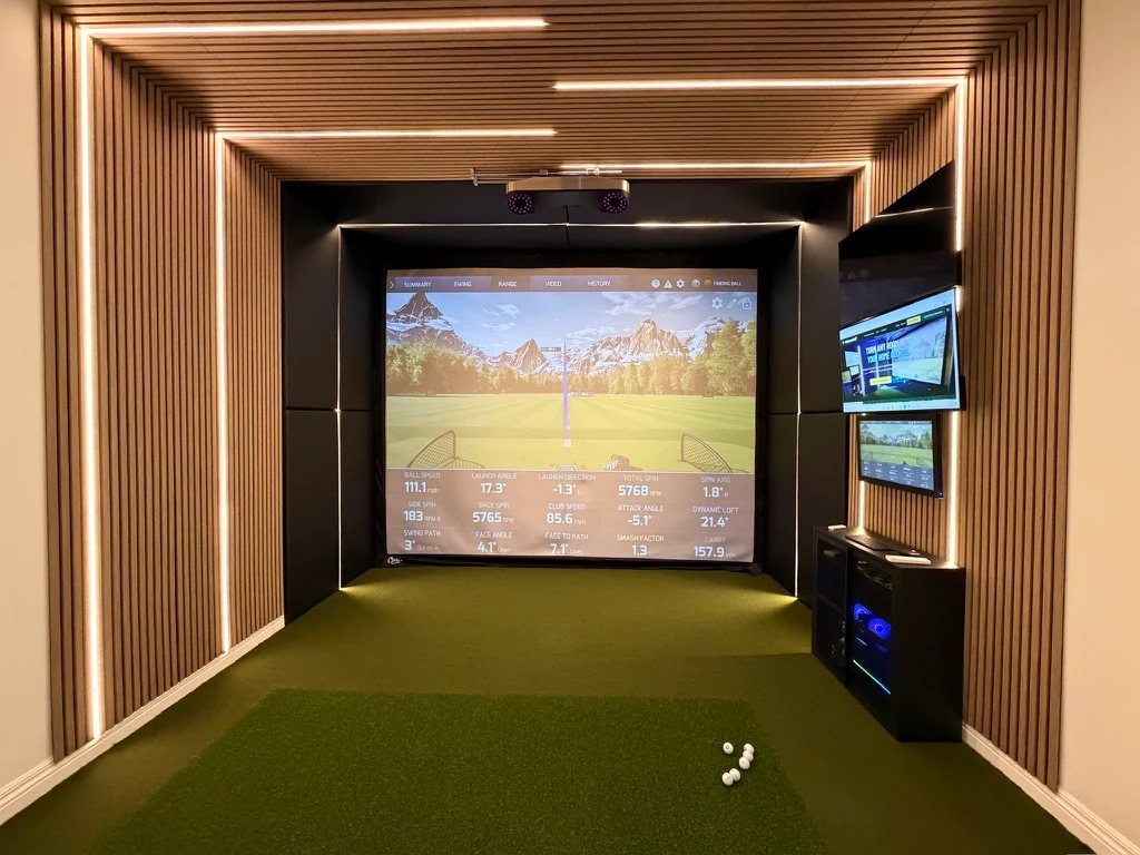 Custom golf simulator room with wood-slat walls and ceiling, integrated lighting, and green turf